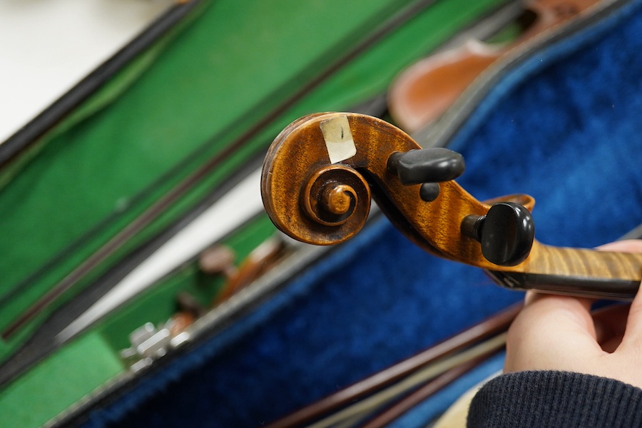 Four cased violins; an early 20th century violin, body 36cm, fitted with a microphone pick up taking a quarter inch jack plug, an early 20th century half size violin, body 32cm, and two student violins. Condition - poor